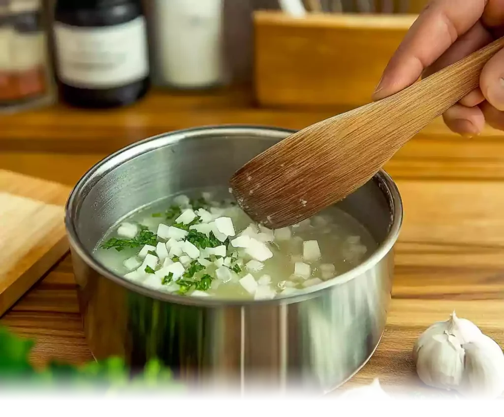 Sautéing diced onions and fresh herbs in a stainless steel pot while preparing Diced Hashbrown Loaded Potato Soup.