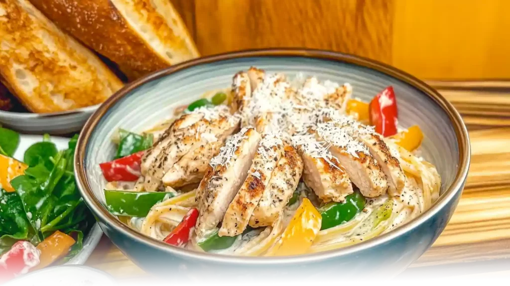 Spicy Chicken Chipotle Pasta served in a bowl, topped with grilled chicken slices, sautéed vegetables, and Parmesan cheese.