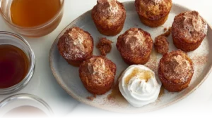 Golden cinnamon sugar French toast muffins served with whipped cream and maple syrup