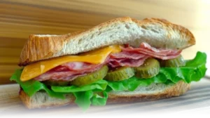 What are good sandwich toppings with lettuce, tomatoes, deli meats, cheddar cheese, and avocado, displayed in a bright, modern kitchen.