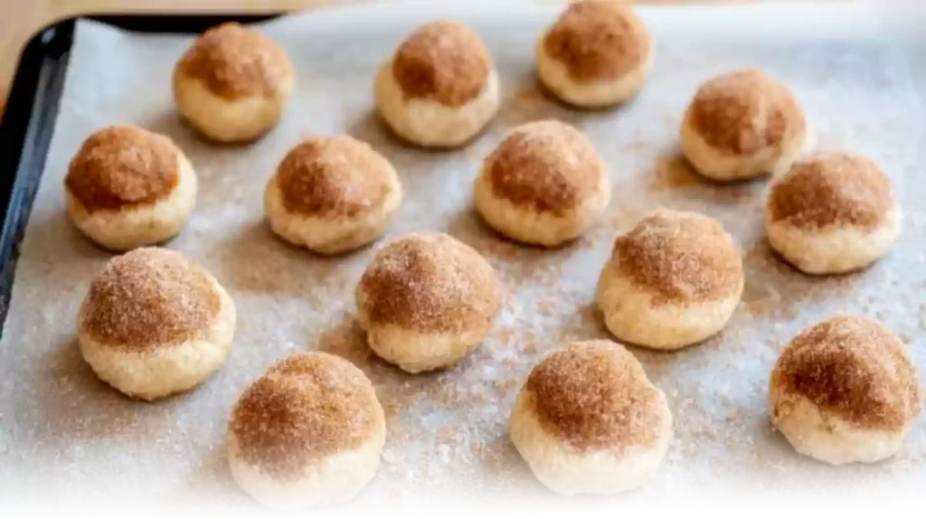 Preparing Churro Cheesecake Cookies: dough balls being filled with cream cheese and rolled in cinnamon sugar in a bright kitchen.