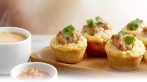 Preparing sausage muffins by folding cooked sausage and cheese into Bisquick batter in a modern kitchen