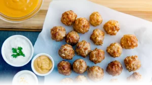 Golden Cheddar Bay Sausage Balls garnished with parsley, served on a platter with dipping sauces in a modern kitchen setting.