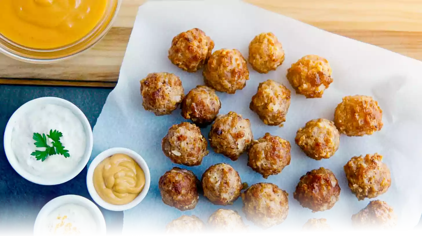 Golden Cheddar Bay Sausage Balls garnished with parsley, served on a platter with dipping sauces in a modern kitchen setting.